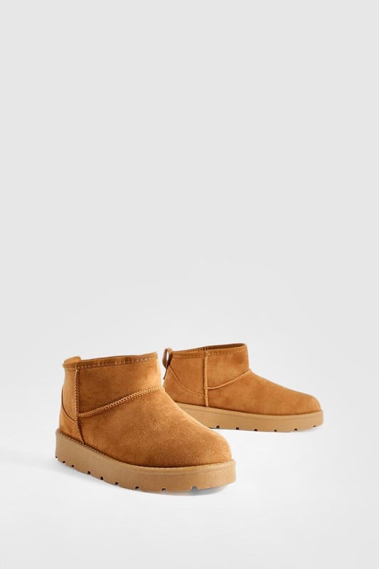 Ultra mini design for a trendy, compact silhouette
        Cosy synthetic suede upper for warmth and comfort
        Slip-on style for easy wear
        Durable synthetic outer sole for traction
        Versatile ankle height suitable for various outfits
    
    Step into comfort and style with these ultra mini cosy boots from Boohoo. Perfect for the fashion-forward woman who values both trend and practicality, these boots offer a snug fit that's ideal for chilly days. The ankle-height design makes them incredibly versatile, pairing effortlessly with everything from skinny jeans to midi skirts. For a laid-back look, team them with oversized knitwear and leggings, or dress them up with a flowy dress and tights for casual outings. These boots are a must-have for family gatherings, coffee dates, or weekend shopping trips. Their compact size makes them an excellent choice for travel, easily fitting into your luggage without sacrificing style. Embrace the cosy-chic trend and make these ultra mini boots your go-to footwear for comfortable, on-trend casual wear.