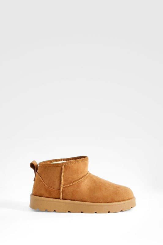 Ultra mini design for a trendy, compact silhouette
        Cosy synthetic suede upper for warmth and comfort
        Slip-on style for easy wear
        Durable synthetic outer sole for traction
        Versatile ankle height suitable for various outfits
    
    Step into comfort and style with these ultra mini cosy boots from Boohoo. Perfect for the fashion-forward woman who values both trend and practicality, these boots offer a snug fit that's ideal for chilly days. The ankle-height design makes them incredibly versatile, pairing effortlessly with everything from skinny jeans to midi skirts. For a laid-back look, team them with oversized knitwear and leggings, or dress them up with a flowy dress and tights for casual outings. These boots are a must-have for family gatherings, coffee dates, or weekend shopping trips. Their compact size makes them an excellent choice for travel, easily fitting into your luggage without sacrificing style. Embrace the cosy-chic trend and make these ultra mini boots your go-to footwear for comfortable, on-trend casual wear.