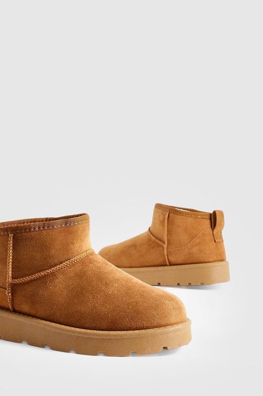 Ultra mini design for a trendy, compact silhouette
        Cosy synthetic suede upper for warmth and comfort
        Slip-on style for easy wear
        Durable synthetic outer sole for traction
        Versatile ankle height suitable for various outfits
    
    Step into comfort and style with these ultra mini cosy boots from Boohoo. Perfect for the fashion-forward woman who values both trend and practicality, these boots offer a snug fit that's ideal for chilly days. The ankle-height design makes them incredibly versatile, pairing effortlessly with everything from skinny jeans to midi skirts. For a laid-back look, team them with oversized knitwear and leggings, or dress them up with a flowy dress and tights for casual outings. These boots are a must-have for family gatherings, coffee dates, or weekend shopping trips. Their compact size makes them an excellent choice for travel, easily fitting into your luggage without sacrificing style. Embrace the cosy-chic trend and make these ultra mini boots your go-to footwear for comfortable, on-trend casual wear.