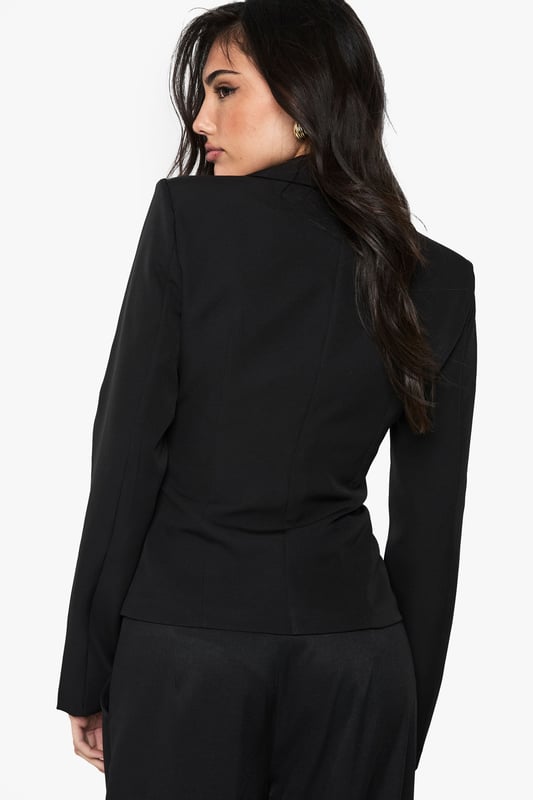 Striking button detail running down the front creates a sophisticated focal point
        Fitted silhouette with cinched waist accentuates your natural curves
        Structured shoulders and lapel collar offer a polished, tailored appearance
        Long sleeves with subtle cuff detail provide a refined finishing touch
        Versatile regular fit allows for comfortable movement whilst maintaining shape
    
    Make a statement with this Button Detail Fitted Cinched Blazer from Boohoo. The expertly tailored silhouette creates a flattering hourglass shape that commands attention, whilst the classic button-up design adds timeless appeal. Perfect for evening occasions, pair with wide-leg trousers as shown for a contemporary power suit that transitions effortlessly from office to nightlife. For a night out, style with a lace camisole underneath, statement jewellery and heels for a look that radiates confidence. The structured design and cinched waist detail make this blazer an essential wardrobe piece that works beautifully for drinks with friends or club nights when you want to combine sophistication with urban edge. The slight stretch in the fabric ensures comfort doesn't compromise on style, allowing you to dance the night away.
