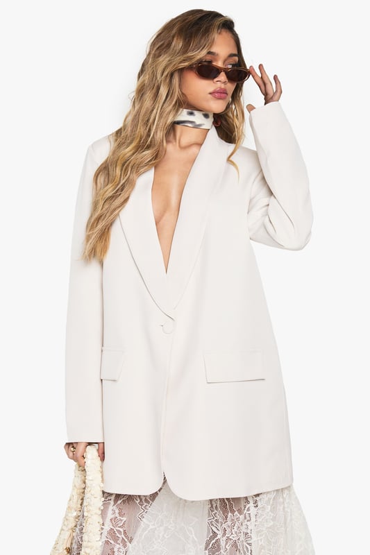 Oversized blazer with structured shoulder pads for a bold silhouette
        Deep plunging neckline creates a dramatic, contemporary look
        Relaxed fit design offers comfortable movement and versatile styling options
        Classic collared detail with notched lapels for timeless appeal
        Functional front pockets add practical detail to this statement piece
    
    Make a striking impression with this Boohoo oversized blazer, designed to command attention with its deep neckline and structured shoulder pads. The relaxed fit creates an effortlessly chic silhouette that works brilliantly for evening occasions. Style it as seen with a delicate lace skirt for an intriguing contrast between tailoring and femininity, or pair with slim-fit trousers and heels for a sophisticated night out look. For an edgier ensemble, throw it over a bodysuit with statement jewellery and your favourite clutch bag. This versatile blazer transitions seamlessly from drinks with friends to club nights, offering that perfect balance of comfort and head-turning style that's essential for your going-out wardrobe. Add sleek sunglasses and minimalist accessories to complete this contemporary urban nightlife look.