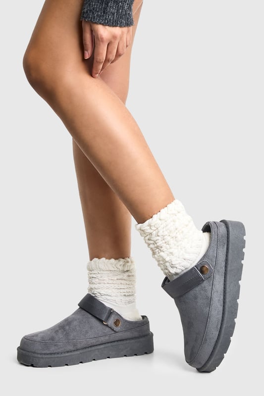 Cosy mule design for ultimate comfort
        Flat heel between 0 and 2cm for easy wear
        Soft, plush upper material for a luxurious feel
        Sturdy sole with textured grip for stability
        Decorative button detail adds a stylish touch
    
    Step into a world of comfort and style with these irresistibly cosy mules from Boohoo. Perfect for those lazy days at home or casual outings, these slip-ons offer the ideal blend of comfort and fashion-forward design. The plush upper material envelops your feet in warmth, while the flat heel ensures all-day wearability. Style these versatile mules with your favourite loungewear for a relaxed day in, or pair them with cropped jeans and an oversized jumper for a chic, off-duty look. Whether you're popping to the shops or meeting friends for a casual brunch, these mules will keep you looking effortlessly stylish and feeling utterly comfortable. The subtle button detail adds a touch of elegance, making these the perfect choice for those who appreciate both comfort and understated sophistication in their footwear.