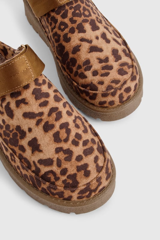 Eye-catching leopard print design
        Cosy mule style for easy slip-on wear
        Flat heel for all-day comfort (0-2cm height)
        Chunky sole for added durability
        Soft, plush lining for extra warmth
    
    Step into wild comfort with these trendy leopard print mules from Boohoo. Perfect for the fashion-forward woman who values both style and cosiness, these slip-ons are ideal for casual outings and relaxed days at home. The flat heel and chunky sole ensure stability and comfort, making them suitable for extended wear. Style them with your favourite loungewear for a chic at-home look, or pair them with cropped jeans and an oversized jumper for a quick coffee run. The versatile design allows for effortless transitioning from indoor relaxation to outdoor errands, embodying the perfect blend of fashion and functionality. Whether you're hosting a casual gathering or running weekend errands, these mules will keep you looking stylish and feeling comfortable throughout the day.