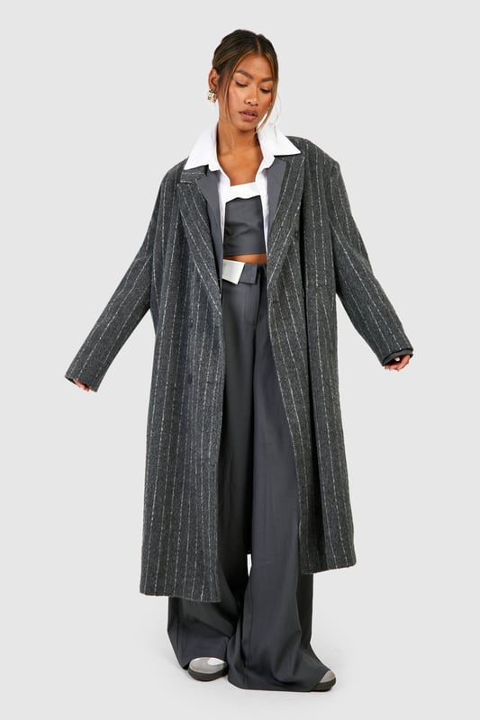 Oversized silhouette for a bold, contemporary look
        Classic pinstripe pattern adds sophistication
        Notched lapels and long sleeves for timeless appeal
        Versatile wool-look fabric suitable for various occasions
        Longline design for dramatic flair and extra warmth
    
    Make a striking statement with this pinstripe oversized coat, perfect for the fashion-forward individual who appreciates a blend of classic and modern styles. The generous cut allows for effortless layering over chunky knits or sleek tailoring, making it an ideal choice for transitional weather. Style it with wide-leg trousers and trainers for a chic, relaxed look, or pair it with a crisp white shirt and tailored trousers for more formal events. The timeless pinstripe pattern ensures this coat will remain a wardrobe staple for seasons to come, while its versatility allows for endless styling possibilities. Whether you're heading to the office, a smart-casual dinner, or a weekend brunch, this coat will keep you looking polished and on-trend.