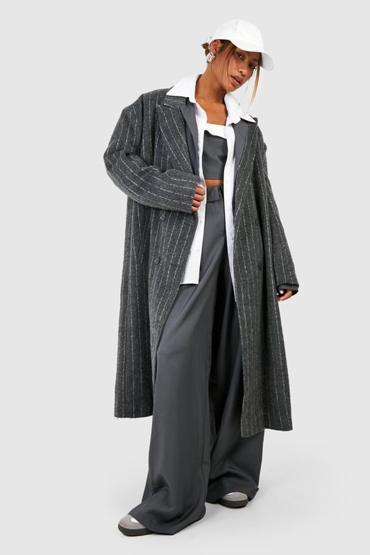 Oversized silhouette for a bold, contemporary look
        Classic pinstripe pattern adds sophistication
        Notched lapels and long sleeves for timeless appeal
        Versatile wool-look fabric suitable for various occasions
        Longline design for dramatic flair and extra warmth
    
    Make a striking statement with this pinstripe oversized coat, perfect for the fashion-forward individual who appreciates a blend of classic and modern styles. The generous cut allows for effortless layering over chunky knits or sleek tailoring, making it an ideal choice for transitional weather. Style it with wide-leg trousers and trainers for a chic, relaxed look, or pair it with a crisp white shirt and tailored trousers for more formal events. The timeless pinstripe pattern ensures this coat will remain a wardrobe staple for seasons to come, while its versatility allows for endless styling possibilities. Whether you're heading to the office, a smart-casual dinner, or a weekend brunch, this coat will keep you looking polished and on-trend.