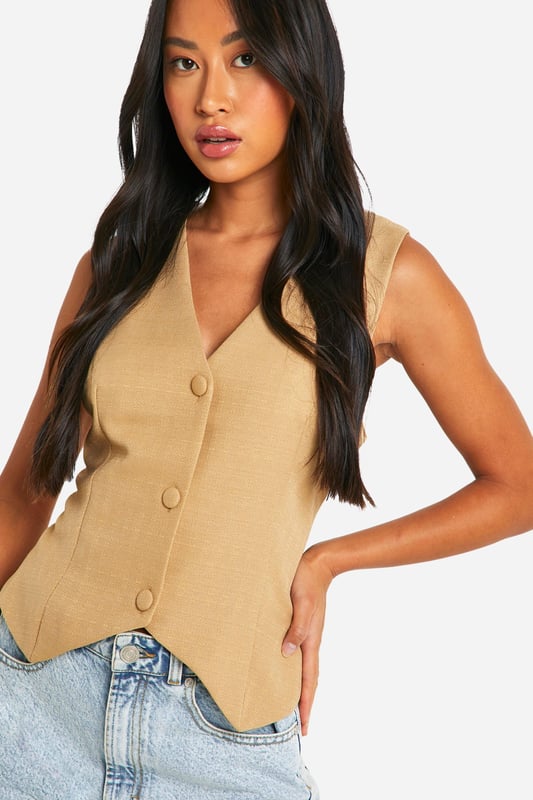 Textured woven crepe fabric for added visual interest
        Sleeveless design with a collared neckline
        Button-front closure for easy wear
        Relaxed fit for comfortable, effortless style
        Charming bow-tie detail at the back for a feminine touch
    
    This structured woven vest from Boohoo is a versatile piece that can effortlessly transition from day to night. The relaxed fit and textured crepe fabric create a laid-back yet polished look, perfect for various casual occasions. Style it with denim shorts and trainers for a chic daytime ensemble, or pair it with tailored trousers and heels for a more sophisticated evening outfit. The button-front closure allows for customisable styling, while the unexpected bow-tie detail at the back adds a playful twist. Ideal for family gatherings, brunches with friends, or casual Fridays at the office, this vest is a must-have addition to your wardrobe. Its adaptable nature makes it suitable for layering in cooler weather or wearing on its own during warmer months, ensuring year-round wearability.