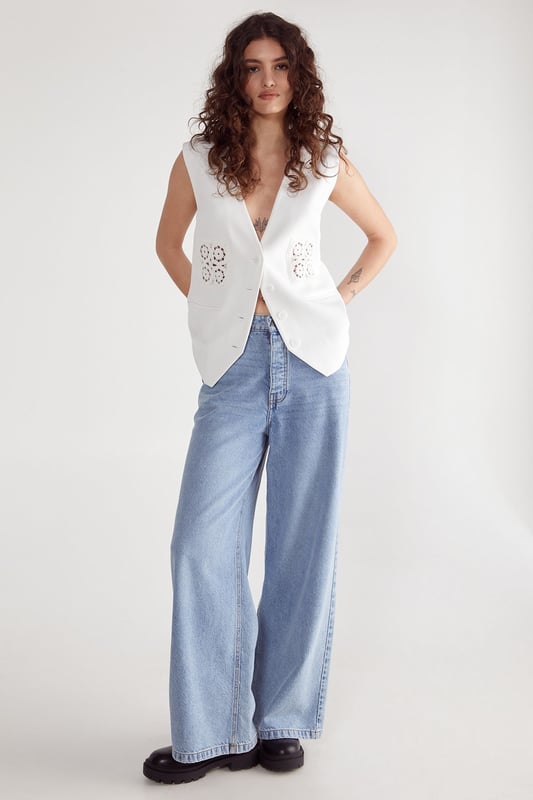 Tailored vest with a sleek, modern silhouette
        Intricate crochet insert detailing for a touch of bohemian charm
        Deep V-neckline creates an elongating effect
        Structured shoulders for a polished look
        Versatile design suitable for both casual and formal occasions
    
    This crochet insert tailored vest from NastyGal is a versatile piece that seamlessly blends sophistication with a hint of bohemian flair. The tailored fit accentuates your silhouette, while the deep V-neckline elongates and flatters. Perfect for layering, this vest can be styled for a range of occasions. For a chic daytime look, pair it with wide-leg trousers and trainers as shown. When dressing for formal events, layer it over a crisp button-down shirt and team with tailored trousers and heels. The crochet insert adds a unique touch, making this vest a standout piece for weddings, races, or graduations. Its adaptability allows for endless styling possibilities, ensuring you'll find multiple ways to incorporate this garment into your wardrobe for years to come.