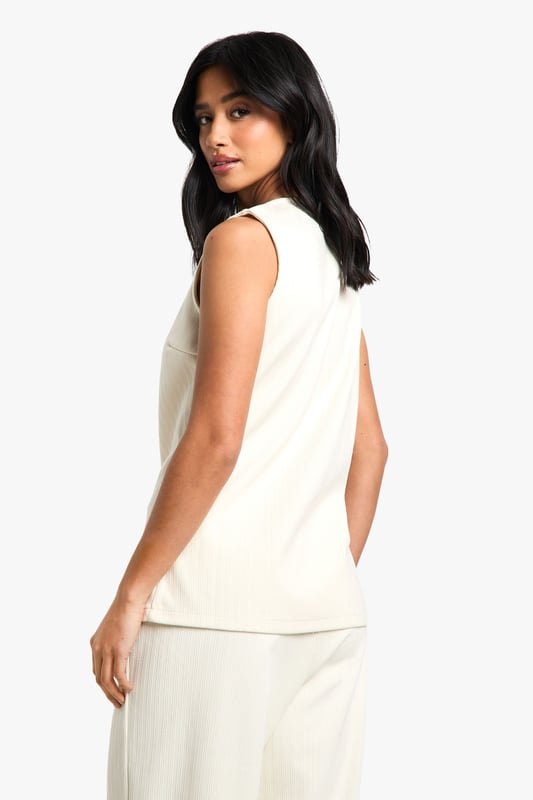 Sleeveless cord waistcoat with high neckline for a sophisticated silhouette
        Asymmetric button-through front detail adding contemporary flair
        Structured woven cotton fabric providing excellent shape retention
        Versatile petite fit designed specifically for smaller frames
        Sleek, clean-lined design perfect for layering or wearing alone
    
    This cord waistcoat reimagines a classic silhouette with modern asymmetric detailing, making it a standout piece for your evening wardrobe. The structured cotton fabric creates a flattering shape that works brilliantly for petite frames, whilst the high neckline adds a touch of sophistication. Style as seen with coordinating wide-leg trousers and pointed heels for a chic monochromatic ensemble that's perfect for drinks with the girls. For cooler evenings, layer over a fitted turtleneck or under a tailored blazer. Alternatively, dress it down with your favourite denim and trainers for casual drinks. The versatile design transitions effortlessly from day to night, making it an essential addition to your Boohoo collection that will see you through multiple social occasions with style and confidence.