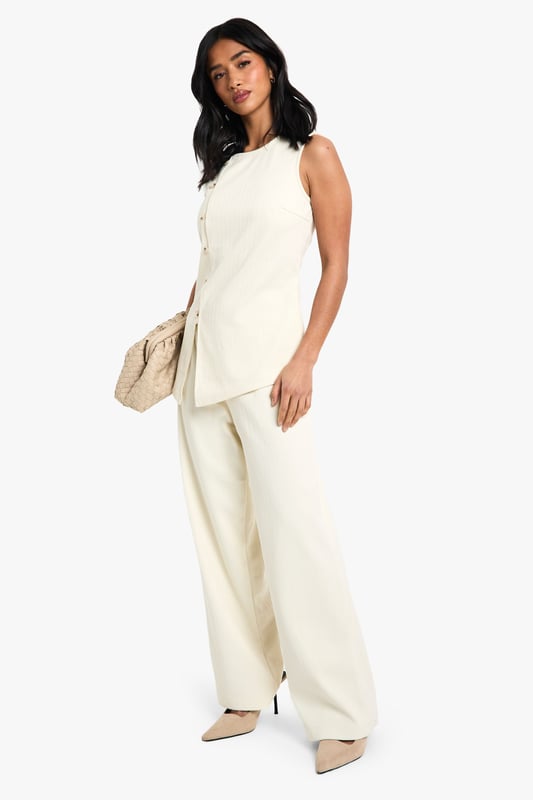 Sleeveless cord waistcoat with high neckline for a sophisticated silhouette
        Asymmetric button-through front detail adding contemporary flair
        Structured woven cotton fabric providing excellent shape retention
        Versatile petite fit designed specifically for smaller frames
        Sleek, clean-lined design perfect for layering or wearing alone
    
    This cord waistcoat reimagines a classic silhouette with modern asymmetric detailing, making it a standout piece for your evening wardrobe. The structured cotton fabric creates a flattering shape that works brilliantly for petite frames, whilst the high neckline adds a touch of sophistication. Style as seen with coordinating wide-leg trousers and pointed heels for a chic monochromatic ensemble that's perfect for drinks with the girls. For cooler evenings, layer over a fitted turtleneck or under a tailored blazer. Alternatively, dress it down with your favourite denim and trainers for casual drinks. The versatile design transitions effortlessly from day to night, making it an essential addition to your Boohoo collection that will see you through multiple social occasions with style and confidence.