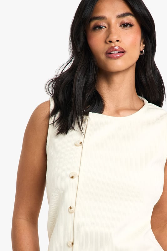 Sleeveless cord waistcoat with high neckline for a sophisticated silhouette
        Asymmetric button-through front detail adding contemporary flair
        Structured woven cotton fabric providing excellent shape retention
        Versatile petite fit designed specifically for smaller frames
        Sleek, clean-lined design perfect for layering or wearing alone
    
    This cord waistcoat reimagines a classic silhouette with modern asymmetric detailing, making it a standout piece for your evening wardrobe. The structured cotton fabric creates a flattering shape that works brilliantly for petite frames, whilst the high neckline adds a touch of sophistication. Style as seen with coordinating wide-leg trousers and pointed heels for a chic monochromatic ensemble that's perfect for drinks with the girls. For cooler evenings, layer over a fitted turtleneck or under a tailored blazer. Alternatively, dress it down with your favourite denim and trainers for casual drinks. The versatile design transitions effortlessly from day to night, making it an essential addition to your Boohoo collection that will see you through multiple social occasions with style and confidence.