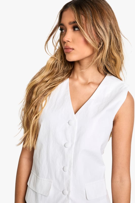 Sleek nylon vest with button-front closure
        V-neckline for a flattering silhouette
        Versatile sleeveless design
        Practical patch pockets at the waist
        Cropped length for a contemporary look
    
    Embrace effortless style with this chic nylon vest from Boohoo. Perfect for the fashion-forward woman who values both trend and versatility, this piece can easily transition from day to night. Layer it over a crisp white shirt and pair with wide-leg trousers for a polished office ensemble, or throw it on over a simple tee with your favourite jeans for a casual weekend look. The button-front closure and v-neckline add a touch of sophistication, while the cropped length keeps it current. Ideal for family gatherings or casual outings with friends, this vest is a wardrobe staple that can be dressed up or down with ease. Its lightweight nylon fabric makes it a practical choice for layering throughout the seasons, ensuring you stay on-trend whatever the weather.