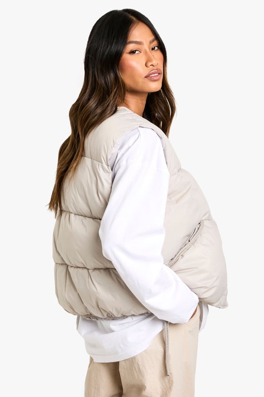 Sleeveless padded gilet with elegant bow detail at the back
        Practical side pockets for essentials and hand-warming
        Versatile round neckline that works with various tops
        Relaxed fit design perfect for layering
        Subtle quilted texture adding dimension to your outfit
    
    This Boohoo gilet offers the perfect blend of practicality and style for your casual wardrobe. The distinctive bow detail at the back transforms an everyday piece into something special, whilst maintaining its effortless wearability. Style as seen with a simple long-sleeved top and wide-leg trousers for a contemporary silhouette that works brilliantly for daytime outings. Add trainers and a baseball cap for an on-trend casual look, or dress up with ankle boots and statement jewellery for lunch with friends. The versatile design makes it ideal for transitional weather, providing just the right amount of warmth without bulk. Perfect for family gatherings, weekend shopping trips or casual coffee dates when you want to look stylish without trying too hard.