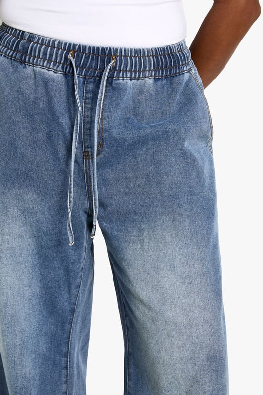 Straight-leg denim jeans with elastic waistband for comfort
        Wide-leg silhouette for a relaxed, on-trend look
        High-rise fit to flatter curves and provide coverage
        Adjustable drawstring for a customisable fit
        Versatile medium wash suitable for various casual occasions
    
    Embrace laid-back chic with these plus-size straight-leg jeans from Boohoo. The elastic waistband and adjustable drawstring offer unparalleled comfort and a personalised fit, perfect for all-day wear. The wide-leg silhouette creates a trendy, relaxed look that's ideal for casual outings. Style these jeans with a fitted white vest top and an oversized denim jacket for an effortlessly cool double denim ensemble. Add a pair of chunky trainers for a street-style edge, or dress them up with block-heel sandals for a casual night out. These versatile jeans are a wardrobe essential, easily transitioning from daytime errands to relaxed evening gatherings with friends. The high-rise fit and straight leg combine to create a flattering silhouette that complements curves beautifully, making these jeans a go-to choice for the fashion-forward woman who values both style and comfort.