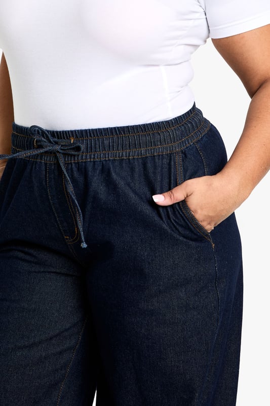 Straight-leg denim jeans with elastic waistband for comfort
        Wide-leg silhouette for a relaxed, on-trend look
        Convenient side pockets for practicality
        Drawstring detail at waist for adjustable fit
        Versatile design suitable for various casual occasions
    
    These plus-size jeans from Boohoo offer a perfect blend of style and comfort for the fashion-forward woman. The straight-leg cut and wide-leg silhouette create a flattering shape that's right on trend. The elastic waistband with drawstring detail ensures a customisable fit, making these jeans ideal for all-day wear. Style them with a crisp white tee and trainers for a laid-back daytime look, or dress them up with a fitted blouse and statement jewellery for casual evening events. The versatile denim fabric makes these jeans a wardrobe staple, easily transitioning from family gatherings to weekend brunches with friends. For a chic autumn ensemble, pair with a trench coat and ankle boots. These jeans embody Boohoo's commitment to inclusive fashion that doesn't compromise on style or comfort.