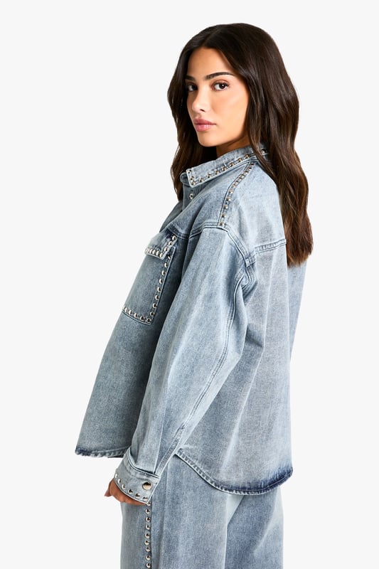 Oversized denim shirt featuring eye-catching stud detailing along the pockets
        Relaxed drop shoulder design for that effortlessly cool aesthetic
        Front button fastening with classic collar for versatile styling options
        Spacious chest pockets with distinctive stud embellishment
        Specially designed for petite frames whilst maintaining the trendy oversized silhouette
    
    This statement denim shirt combines casual comfort with edgy detailing, perfect for the fashion-forward woman who loves to make an impression. The oversized fit creates a relaxed silhouette that works brilliantly when paired with matching denim for a coordinated ensemble, as shown by our model. Layer over a simple vest top and team with wide-leg trousers for a contemporary daytime look, or half-tuck into high-waisted jeans for a more defined shape. The stud detailing adds a touch of attitude to casual gatherings and weekend brunches. For cooler days, style under an oversized blazer with trainers for an on-trend casual outfit, or dress up with ankle boots and statement jewellery for evening drinks. This versatile Boohoo piece transitions effortlessly from day to night whilst maintaining that coveted laid-back vibe.