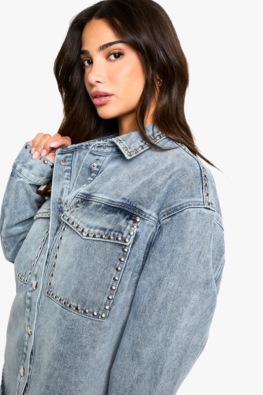 Oversized denim shirt featuring eye-catching stud detailing along the pockets
        Relaxed drop shoulder design for that effortlessly cool aesthetic
        Front button fastening with classic collar for versatile styling options
        Spacious chest pockets with distinctive stud embellishment
        Specially designed for petite frames whilst maintaining the trendy oversized silhouette
    
    This statement denim shirt combines casual comfort with edgy detailing, perfect for the fashion-forward woman who loves to make an impression. The oversized fit creates a relaxed silhouette that works brilliantly when paired with matching denim for a coordinated ensemble, as shown by our model. Layer over a simple vest top and team with wide-leg trousers for a contemporary daytime look, or half-tuck into high-waisted jeans for a more defined shape. The stud detailing adds a touch of attitude to casual gatherings and weekend brunches. For cooler days, style under an oversized blazer with trainers for an on-trend casual outfit, or dress up with ankle boots and statement jewellery for evening drinks. This versatile Boohoo piece transitions effortlessly from day to night whilst maintaining that coveted laid-back vibe.