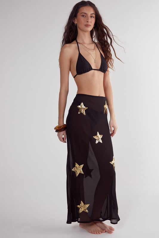 Midi-length beach skirt featuring eye-catching star sequin embellishments
        Lightweight woven fabric perfect for warm-weather destinations
        Flattering silhouette with a comfortable fit that moves with you
        Sheer design ideal for layering over swimwear
        Versatile piece that transitions effortlessly from beach to bar
    
    Make a statement on your next beach holiday with this show-stopping Star Embellished Midi Beach Skirt from Nasty Gal. The striking star sequin detailing catches the light beautifully as you stroll along the shoreline or lounge by the pool. Style it as seen with a matching triangle bikini top for a coordinated beach look, or pair with a simple bandeau and oversized sunglasses for effortless glamour. The semi-sheer fabric offers just the right amount of coverage whilst maintaining that essential holiday vibe. Perfect for sunset cocktails, simply add a loose linen shirt and some metallic sandals to transform your daytime beach ensemble into an evening-ready outfit. This skirt is a must-have addition to your holiday wardrobe, promising to turn heads wherever your sunny adventures take you.