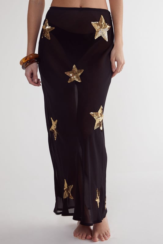 Midi-length beach skirt featuring eye-catching star sequin embellishments
        Lightweight woven fabric perfect for warm-weather destinations
        Flattering silhouette with a comfortable fit that moves with you
        Sheer design ideal for layering over swimwear
        Versatile piece that transitions effortlessly from beach to bar
    
    Make a statement on your next beach holiday with this show-stopping Star Embellished Midi Beach Skirt from Nasty Gal. The striking star sequin detailing catches the light beautifully as you stroll along the shoreline or lounge by the pool. Style it as seen with a matching triangle bikini top for a coordinated beach look, or pair with a simple bandeau and oversized sunglasses for effortless glamour. The semi-sheer fabric offers just the right amount of coverage whilst maintaining that essential holiday vibe. Perfect for sunset cocktails, simply add a loose linen shirt and some metallic sandals to transform your daytime beach ensemble into an evening-ready outfit. This skirt is a must-have addition to your holiday wardrobe, promising to turn heads wherever your sunny adventures take you.