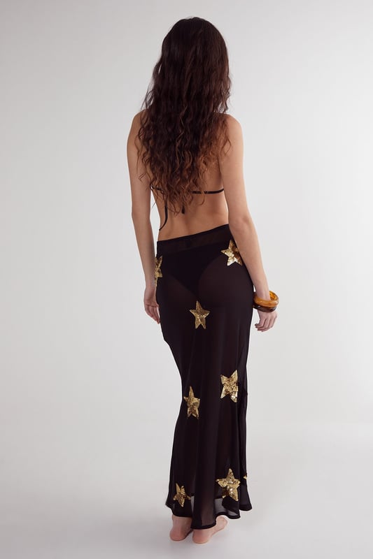 Midi-length beach skirt featuring eye-catching star sequin embellishments
        Lightweight woven fabric perfect for warm-weather destinations
        Flattering silhouette with a comfortable fit that moves with you
        Sheer design ideal for layering over swimwear
        Versatile piece that transitions effortlessly from beach to bar
    
    Make a statement on your next beach holiday with this show-stopping Star Embellished Midi Beach Skirt from Nasty Gal. The striking star sequin detailing catches the light beautifully as you stroll along the shoreline or lounge by the pool. Style it as seen with a matching triangle bikini top for a coordinated beach look, or pair with a simple bandeau and oversized sunglasses for effortless glamour. The semi-sheer fabric offers just the right amount of coverage whilst maintaining that essential holiday vibe. Perfect for sunset cocktails, simply add a loose linen shirt and some metallic sandals to transform your daytime beach ensemble into an evening-ready outfit. This skirt is a must-have addition to your holiday wardrobe, promising to turn heads wherever your sunny adventures take you.