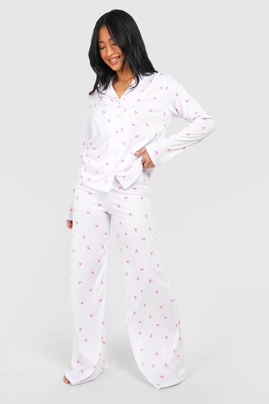 Charming bow print pyjama set
        Soft jersey fabric for ultimate comfort
        Long-sleeved button-up top with notched collar
        Wide-leg trousers for unrestricted movement
        Petite fit designed for shorter frames
    
    Indulge in a night of sweet dreams with this adorable pyjama set from Boohoo. The all-over bow print adds a playful touch to your bedtime routine, while the soft jersey fabric ensures a cosy night's sleep. The long-sleeved top features a classic button-up front and notched collar, perfect for those chilly evenings. Paired with wide-leg trousers, this set offers both style and comfort, allowing for easy movement as you lounge or sleep. Ideal for petite frames, this pyjama set is a must-have addition to your nightwear collection. Whether you're having a relaxing night in or hosting a slumber party with your besties, these pyjamas will keep you looking cute and feeling comfortable all night long.