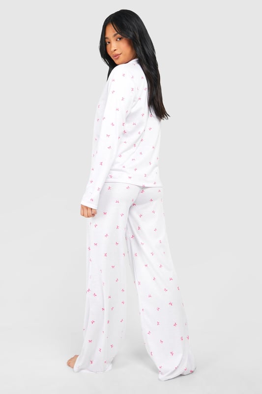Charming bow print pyjama set
        Soft jersey fabric for ultimate comfort
        Long-sleeved button-up top with notched collar
        Wide-leg trousers for unrestricted movement
        Petite fit designed for shorter frames
    
    Indulge in a night of sweet dreams with this adorable pyjama set from Boohoo. The all-over bow print adds a playful touch to your bedtime routine, while the soft jersey fabric ensures a cosy night's sleep. The long-sleeved top features a classic button-up front and notched collar, perfect for those chilly evenings. Paired with wide-leg trousers, this set offers both style and comfort, allowing for easy movement as you lounge or sleep. Ideal for petite frames, this pyjama set is a must-have addition to your nightwear collection. Whether you're having a relaxing night in or hosting a slumber party with your besties, these pyjamas will keep you looking cute and feeling comfortable all night long.