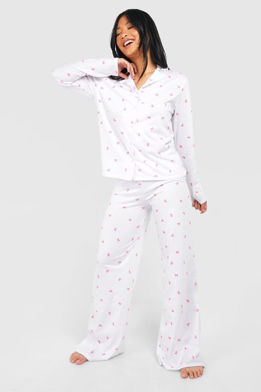 Charming bow print pyjama set
        Soft jersey fabric for ultimate comfort
        Long-sleeved button-up top with notched collar
        Wide-leg trousers for unrestricted movement
        Petite fit designed for shorter frames
    
    Indulge in a night of sweet dreams with this adorable pyjama set from Boohoo. The all-over bow print adds a playful touch to your bedtime routine, while the soft jersey fabric ensures a cosy night's sleep. The long-sleeved top features a classic button-up front and notched collar, perfect for those chilly evenings. Paired with wide-leg trousers, this set offers both style and comfort, allowing for easy movement as you lounge or sleep. Ideal for petite frames, this pyjama set is a must-have addition to your nightwear collection. Whether you're having a relaxing night in or hosting a slumber party with your besties, these pyjamas will keep you looking cute and feeling comfortable all night long.