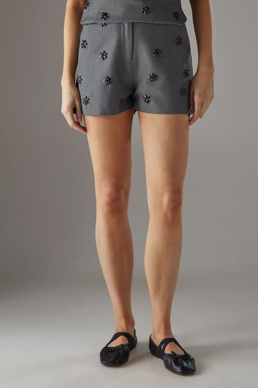 Sophisticated tailored shorts featuring delicate embellishment throughout for a distinctive look
        High-waisted design with a clean, streamlined silhouette for a flattering fit
        Subtle back pockets maintain the sleek aesthetic while offering practicality
        Versatile mid-thigh length perfect for both day and evening occasions
        Slight stretch in the fabric ensures comfort without compromising on structure
    
    These embellished tailored shorts from Warehouse showcase refined craftsmanship with their structured silhouette and eye-catching embellishments. The high-waisted design creates a leg-lengthening effect whilst the tailored cut offers a sophisticated edge to your going-out wardrobe. Style with a matching embellished top as shown for a coordinated set that commands attention, or break up the look with a crisp white blouse for cocktail events. For evening soires, pair with strappy heels and statement jewellery to amplify the glamour. When the temperature drops, layer with a cropped blazer to maintain the polished aesthetic. These shorts transition seamlessly from sunset drinks to late-night dancing, making them a versatile addition to your night-out collection.