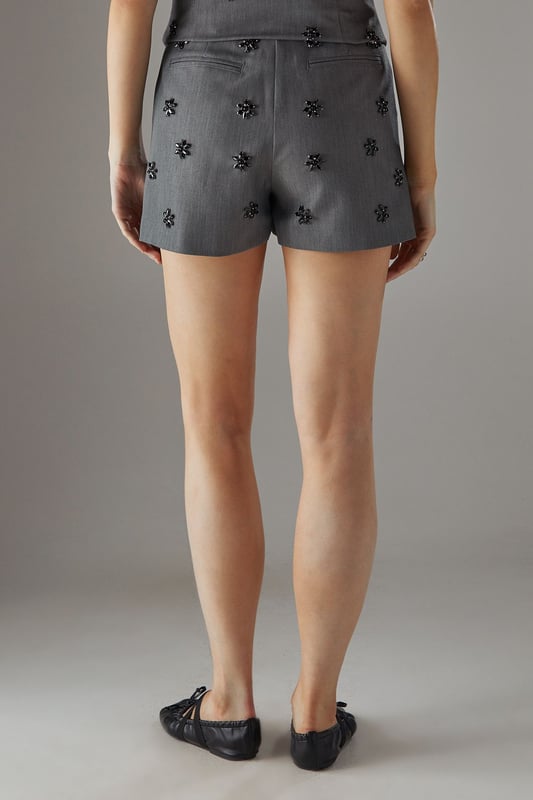 Sophisticated tailored shorts featuring delicate embellishment throughout for a distinctive look
        High-waisted design with a clean, streamlined silhouette for a flattering fit
        Subtle back pockets maintain the sleek aesthetic while offering practicality
        Versatile mid-thigh length perfect for both day and evening occasions
        Slight stretch in the fabric ensures comfort without compromising on structure
    
    These embellished tailored shorts from Warehouse showcase refined craftsmanship with their structured silhouette and eye-catching embellishments. The high-waisted design creates a leg-lengthening effect whilst the tailored cut offers a sophisticated edge to your going-out wardrobe. Style with a matching embellished top as shown for a coordinated set that commands attention, or break up the look with a crisp white blouse for cocktail events. For evening soires, pair with strappy heels and statement jewellery to amplify the glamour. When the temperature drops, layer with a cropped blazer to maintain the polished aesthetic. These shorts transition seamlessly from sunset drinks to late-night dancing, making them a versatile addition to your night-out collection.