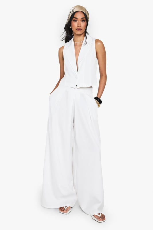Wide leg silhouette for a relaxed, flowing fit
        High-waisted design with pleated front detail
        Sleek side pockets for practicality
        Cropped, sleeveless top with plunging neckline
        Versatile two-piece set for mix-and-match styling
    
    Make a statement in this chic wide-leg trouser set that combines comfort with urban sophistication. The high-waisted design elongates your silhouette, while the pleated front adds a touch of tailored elegance. Pair with the matching cropped top for a coordinated look that's perfect for a night out on the town. The plunging neckline of the top adds a daring edge, ideal for those looking to turn heads at the bar or club. For a more versatile approach, style the trousers with a fitted bodysuit and strappy heels, or dress down the top with high-waisted jeans for drinks with friends. This set is a must-have for the fashion-forward woman who values both style and comfort in her nightlife wardrobe. Accessorise with bold jewellery and a clutch bag to complete your going-out ensemble.