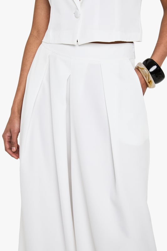 Wide leg silhouette for a relaxed, flowing fit
        High-waisted design with pleated front detail
        Sleek side pockets for practicality
        Cropped, sleeveless top with plunging neckline
        Versatile two-piece set for mix-and-match styling
    
    Make a statement in this chic wide-leg trouser set that combines comfort with urban sophistication. The high-waisted design elongates your silhouette, while the pleated front adds a touch of tailored elegance. Pair with the matching cropped top for a coordinated look that's perfect for a night out on the town. The plunging neckline of the top adds a daring edge, ideal for those looking to turn heads at the bar or club. For a more versatile approach, style the trousers with a fitted bodysuit and strappy heels, or dress down the top with high-waisted jeans for drinks with friends. This set is a must-have for the fashion-forward woman who values both style and comfort in her nightlife wardrobe. Accessorise with bold jewellery and a clutch bag to complete your going-out ensemble.