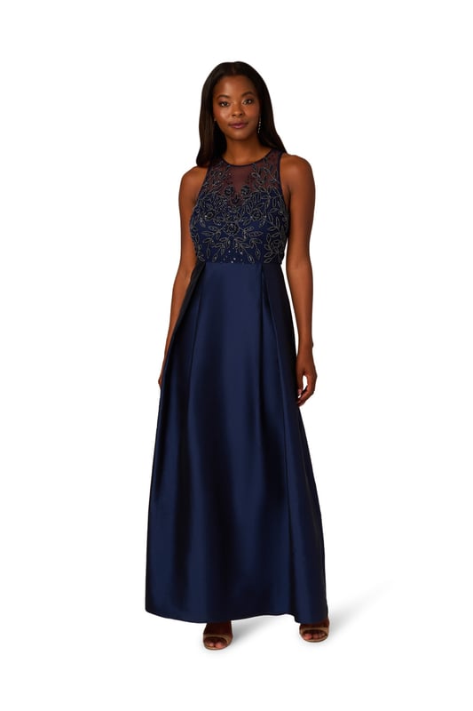 A pinnacle of glamor, youll love getting dressed up in this sleeveless ball gown. The bodice of this exquisite gown is adorned with an all-over beaded embellished mesh knit fabric, catching the light with every step. A crew neckline and illusion sweetheart bodice add sophistication and allure, while the flowing taffeta skirt exudes luxury and grace. Finished with a discreet zipper at the center back, this gown ensures a flawless fit and effortless movement, making it perfect for black-tie events where timeless style and sophistication are essential.