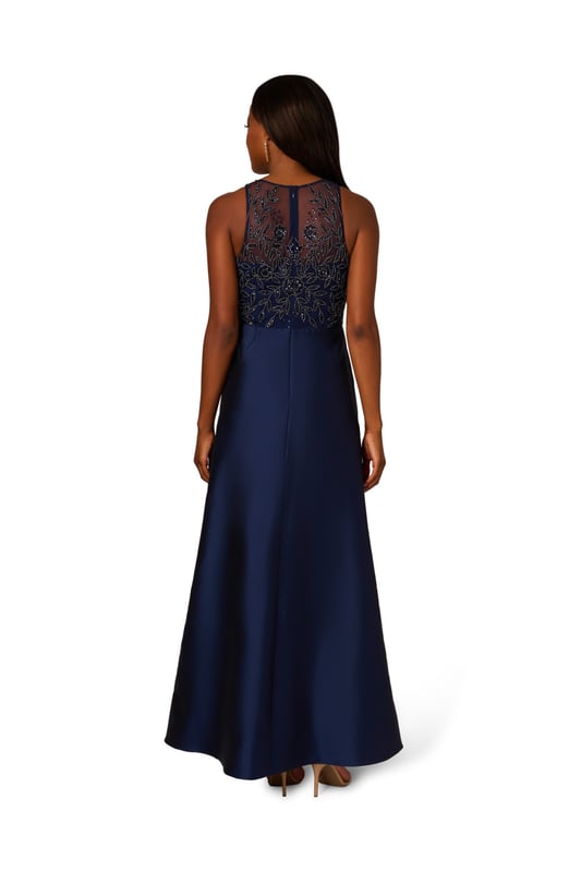 A pinnacle of glamor, youll love getting dressed up in this sleeveless ball gown. The bodice of this exquisite gown is adorned with an all-over beaded embellished mesh knit fabric, catching the light with every step. A crew neckline and illusion sweetheart bodice add sophistication and allure, while the flowing taffeta skirt exudes luxury and grace. Finished with a discreet zipper at the center back, this gown ensures a flawless fit and effortless movement, making it perfect for black-tie events where timeless style and sophistication are essential.