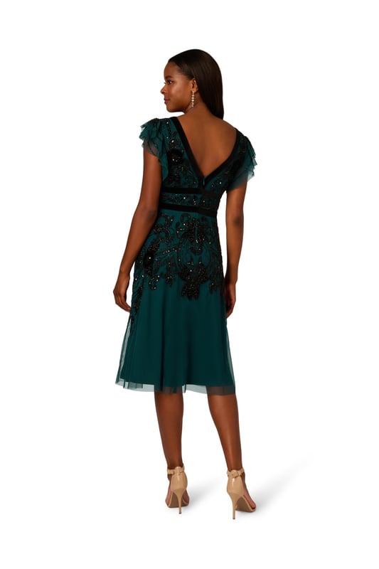 Elevate your evening attire with our stunning midi dress, crafted from an exquisite all-over beaded mesh knit fabric. The V-neckline at both front and back creates a flattering silhouette, complemented by delicate flutter sleeves for a touch of femininity. Velvet trim detailing at the neckline and waist adds luxurious contrast, while the zipper closure at the centre back ensures a seamless fit. Perfect for formal occasions or special events, this dress effortlessly combines elegance and allure, making it a standout choice for any sophisticated affair.