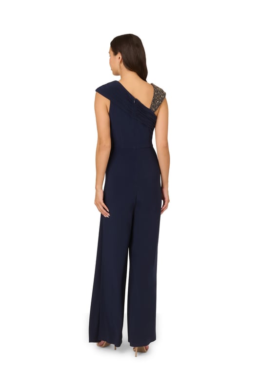 Create a look that sparkles in this wide leg jersey jumpsuit. This jumpsuit features a fitted bodice with shirring at the waist and sleeve, an asymmetrical neckline, and wide legs. Crafted from jersey fabric that has a nice level of stretch for all-night comfort, this jumpsuit is beaded at the shoulder strap. A hidden zipper closure at the centre back completes this dressy jumpsuit. Paired with metallic high heels and sparkling jewellery, this jumpsuit will shine from cocktail attire events to formal weddings.