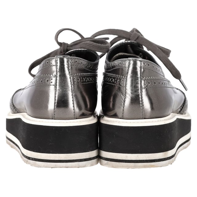 Vintage, Neupreis wie neu  
Bereiten Sie sich darauf vor, Blicke auf sich zu ziehen mit den Prada Metallic Brogue Platform Low Top Sneakers aus silbernem Leder. Diese Sneakers vereinen nahtlos High Fashion und Alltagskomfort. Hergestellt aus luxuriösem metallic Leder, verfügen sie über klassische Wingtip-Brogue-Details und elegante Schnürverschlüsse, die für einen raffinierten, aber lässigen Look sorgen. Die Plattformsohle bietet zusätzliche Höhe und eine einzigartige Note, während die bequemen Einlegesohlen für einen gepolsterten Tragekomfort den ganzen Tag über sorgen. Kombinieren Sie diese Sneakers mit einem plissierten Midirock und einem Blazer für eine unerwartete Mischung aus formell und lässig oder setzen Sie auf einen monochromen Look mit einer silberfarbenen Jacke und maßgeschneiderten Hosen, um das metallische Thema durchgehend zu gestalten.

mit Staubbeutel

Prada Metallic Brogue Platform Low Top Sneakers aus silbernem Leder  
Zustand: Sehr gut  
Tragespuren: Leicht gebraucht, aber sehr gut gepflegt. Kleine Makel an den Sohlen & Faltenbildung, leichte Abnutzung an den Sohlen und Absätzen. Keine sichtbaren Abnutzungsspuren. Kein Makel an der Einlegesohle.  
Verpackung: Staubbeutel  
Farbe: Silber  
Material: Leder | Leder  
Größe: EU | 40,5  
Maße: Absatzhöhe: 50; Einlegesohlenlänge: 290  
SKU: NAPPUGBSH462916W