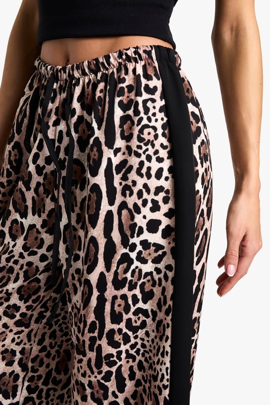 Eye-catching leopard print pattern
        Flattering wide-leg silhouette
        Contrasting side stripes for added flair
        High-waisted design for a lengthening effect
        Lightweight woven fabric for all-day comfort
    
    Make a bold statement with these striking leopard print trousers, perfect for the fashion-forward Boohoo girl. The wide-leg cut offers a relaxed fit that's both on-trend and comfortable, while the high waist creates a flattering silhouette. The contrasting side stripes add a sporty edge, making these trousers versatile enough for various casual occasions. Style them with a cropped black top and trainers for a laid-back daytime look, or dress them up with a sleek bodysuit and heels for a night out with friends. These trousers are ideal for family gatherings, brunch dates, or casual shopping trips. The lightweight fabric ensures you'll stay cool and comfortable, no matter where your day takes you. Embrace your wild side and stand out from the crowd in these eye-catching trousers that perfectly blend comfort with cutting-edge style.