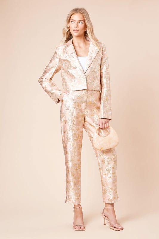 Elegant jacquard fabric with a lustrous finish and textured floral pattern
        Sophisticated tapered fit that narrows towards the ankle for a refined silhouette
        Practical side pockets for essential items
        Flattering high-waist design with a sleek waistband
        Ankle-length cut with subtle side slits for enhanced movement and style
    
    These Dorothy Perkins Tailored Jacquard Tapered Trousers offer the perfect balance of sophistication and contemporary style. The exquisite jacquard weave creates a textured finish that catches the light beautifully, making these trousers ideal for special occasions. Style with a crisp white blouse and strappy heels as shown for elegant wedding guest attire, or pair with a coordinating jacquard blazer for a striking head-to-toe look at formal events. The tapered silhouette creates a flattering shape that works wonderfully for race day ensembles or graduation ceremonies. For evening affairs, match with a simple camisole and statement jewellery to let the trousers take centre stage. These versatile occasion trousers transition seamlessly from day to night, offering endless styling possibilities for the fashion-conscious woman who appreciates refined elegance with a contemporary twist.