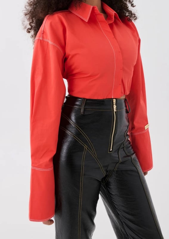 100% Cotton. Cropped fit with a concealed centre front button closure. Contrasting white stitching. Exaggerated sleeves and elongated cuffs. Elasticated around the waist