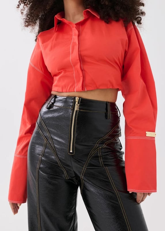 100% Cotton. Cropped fit with a concealed centre front button closure. Contrasting white stitching. Exaggerated sleeves and elongated cuffs. Elasticated around the waist