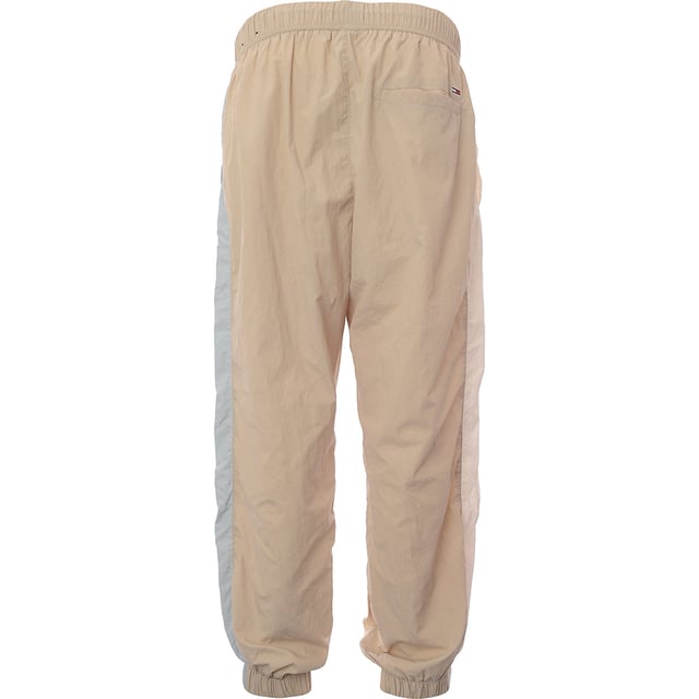 Main: 100% Polyamide. Tommy Jeans nylon blend joggers in beige are the epitome of comfort meets style. With their snug cuffed legs, they offer a modern silhouette that's perfect for a relaxed weekend or a casual outing. The subtle thick stripe down the side adds a touch of sporty elegance, making them a versatile addition to any wardrobe. Whether you're lounging at home or stepping out for a coffee, these joggers blend functionality with a trendy aesthetic.