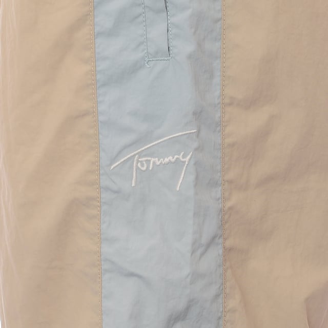 Main: 100% Polyamide. Tommy Jeans nylon blend joggers in beige are the epitome of comfort meets style. With their snug cuffed legs, they offer a modern silhouette that's perfect for a relaxed weekend or a casual outing. The subtle thick stripe down the side adds a touch of sporty elegance, making them a versatile addition to any wardrobe. Whether you're lounging at home or stepping out for a coffee, these joggers blend functionality with a trendy aesthetic.