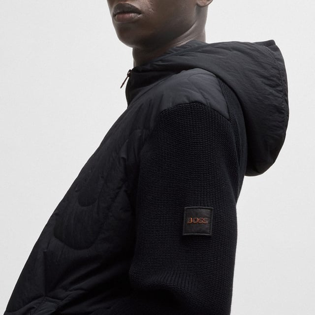 Mens BOSS Kalbero Relaxed Fit Padded Jacket in black.new seasonal design quilting on a light weight padded nylon - sleeves and back in half cardigan rib - double rib hem and cuffs with outside linking - front zip attached on top - visible press button with logo at pockets - squared logo at back inside - light weight padded hood with elasticated binding at opening - new herringbone logo patch at sleeve - 94% cotton 5% polyamide 1% elastane