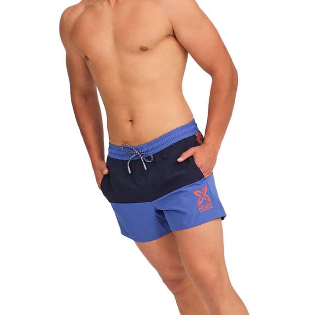 Este bañador hombre corto ofrece un diseño fresco y moderno, ideal para aquellos que buscan comodidad y estilo en sus actividades acuáticas o en días de descanso al sol. Con su tejido ligero y detalles prácticos, es el bañador de hombre perfecto para disfrutar del verano.

Detalles:
- Cintura elástica ajustable con cordón.
- Bolsillos laterales.
- Etiqueta de silicona con relieve en la parte trasera.
- Forro interior de malla.
- Gráficos de la marca.
- Confeccionado en tejido ligero de secado rápido.

Los bañadores de hombre son una prenda indispensable para aquellos que aman disfrutar del agua, ya sea en la playa, en la piscina, o en cualquier otro lugar. Aunque a menudo se consideran como una prenda simple y funcional, el bañador hombre de Munich puede ser una elección de estilo y moda. El bañador largo hombre es una prenda que nos define, por lo que resulta importante dar con un bañador de hombre que nos ayude a proyectar nuestra personalidad.
 Composición: 100% Poliéster
 Cuidados:
Lavar a mano.
No usar lejía ni suavizantes.
Secar al aire libre.