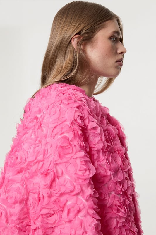 Experience elevated glamour in our cape, which boasts a cropped length, and a textured design with floral appliques. Wear it over a slinky jumpsuit to add an extra level of elegance, or over the matching occasion dress to protect from the elements at upcoming winter events. Textured Rosette Woven Cropped Cape Dramatic Rosette Design Statement Flared Fit Textured, Three Dimensional Floral Applique Cropped Length Matching Dress Sold Separately