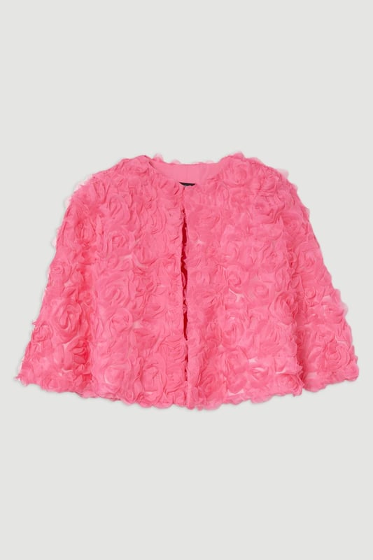 Experience elevated glamour in our cape, which boasts a cropped length, and a textured design with floral appliques. Wear it over a slinky jumpsuit to add an extra level of elegance, or over the matching occasion dress to protect from the elements at upcoming winter events. Textured Rosette Woven Cropped Cape Dramatic Rosette Design Statement Flared Fit Textured, Three Dimensional Floral Applique Cropped Length Matching Dress Sold Separately