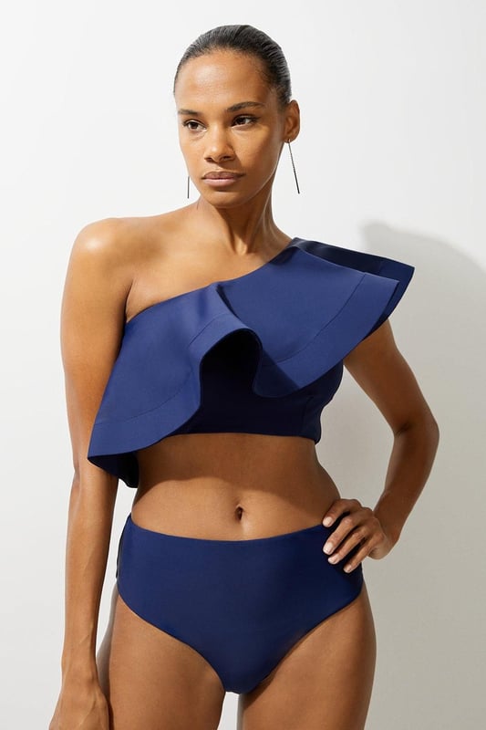 Drama Ruffle One Shoulder Bikini Top Welcome the sun with a bikini that will turn heads, featuring a statement one shoulder design, and a ruffle accent perfect for attracting attention. Style this piece with the matching bikini bottoms, strappy sandals, and a beach cover up for a holiday look that can be reworn time and time again. Drama Ruffle One Shoulder Bikini Top Statement Large Ruffle Detail Flattering One Shoulder Design Comfortable Bandeau Design Matching Bottoms Sold Separately