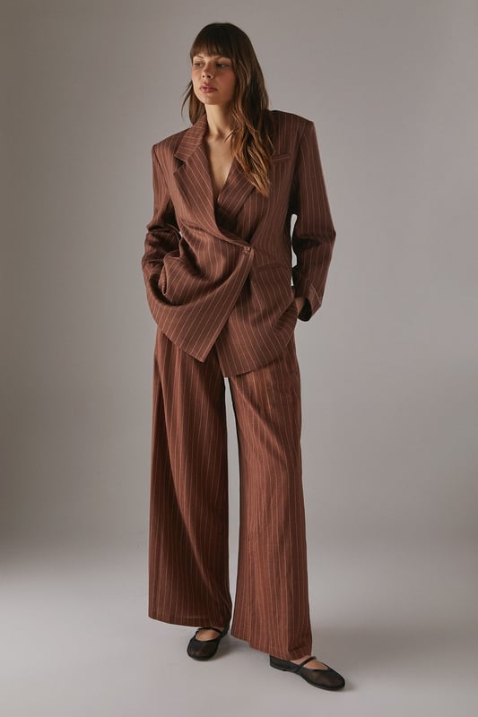 Boxy fit blazer with classic pinstripe pattern for a contemporary twist on tailoring
        Single button fastening creates a clean, streamlined silhouette
        Notched lapel collar adds traditional tailoring detail
        Long sleeves with structured shoulders for a confident, defined shape
        Linen-look fabric offers a textured finish with natural drape
    
    This Warehouse blazer redefines casual sophistication with its relaxed boxy silhouette and distinctive pinstripe pattern. The linen-look fabric creates a textured appearance whilst maintaining a fluid drape that moves beautifully with the body. Style as seen with the matching wide-leg trousers for a coordinated suit that conveys confidence without trying too hard. For daytime engagements, pair with a simple t-shirt and trainers for an effortlessly cool look. When evening calls, swap for a silk camisole and statement jewellery. This versatile piece transitions seamlessly from family gatherings to casual office environments, and even weekend brunches. The relaxed structure makes it ideal for layering over lightweight knits during transitional seasons, whilst the timeless pinstripe pattern ensures this blazer will remain a wardrobe staple for years to come.