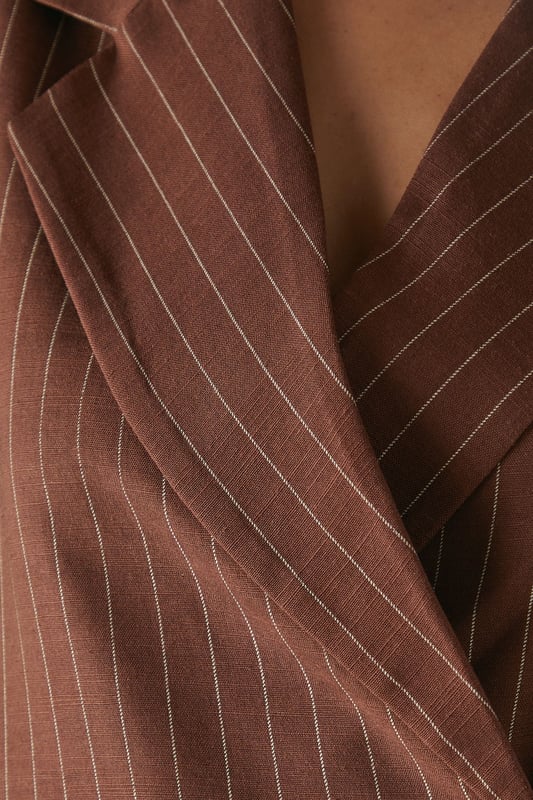 Boxy fit blazer with classic pinstripe pattern for a contemporary twist on tailoring
        Single button fastening creates a clean, streamlined silhouette
        Notched lapel collar adds traditional tailoring detail
        Long sleeves with structured shoulders for a confident, defined shape
        Linen-look fabric offers a textured finish with natural drape
    
    This Warehouse blazer redefines casual sophistication with its relaxed boxy silhouette and distinctive pinstripe pattern. The linen-look fabric creates a textured appearance whilst maintaining a fluid drape that moves beautifully with the body. Style as seen with the matching wide-leg trousers for a coordinated suit that conveys confidence without trying too hard. For daytime engagements, pair with a simple t-shirt and trainers for an effortlessly cool look. When evening calls, swap for a silk camisole and statement jewellery. This versatile piece transitions seamlessly from family gatherings to casual office environments, and even weekend brunches. The relaxed structure makes it ideal for layering over lightweight knits during transitional seasons, whilst the timeless pinstripe pattern ensures this blazer will remain a wardrobe staple for years to come.