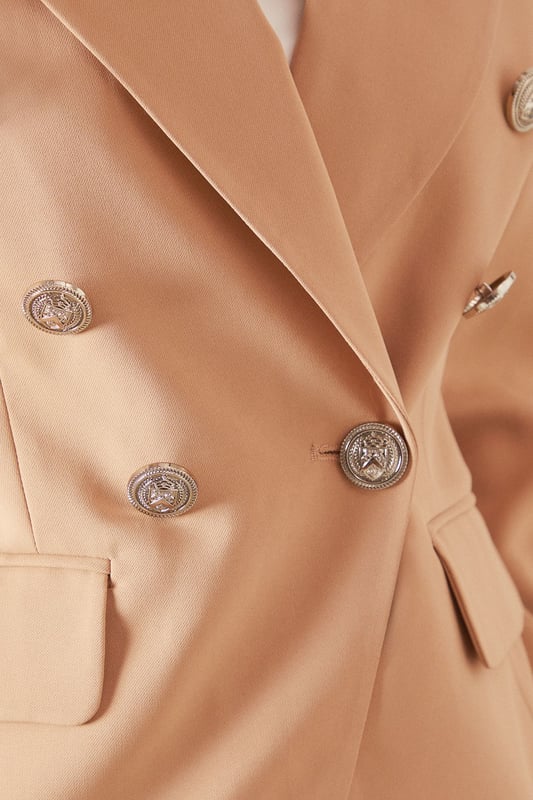 Double-breasted design with striking metallic button detailing for a sophisticated silhouette
        Tailored notched lapels that frame the face beautifully
        Structured shoulders creating a refined, feminine shape
        Functional front flap pockets adding practical elegance
        Decorative sleeve buttons that enhance the tailored finish
    
    This petite double-breasted blazer offers the perfect balance of sophistication and contemporary style. Designed specifically for smaller frames, it creates a flattering silhouette without overwhelming your proportions. The structured shoulders and defined waist work harmoniously to create a polished look suitable for both professional settings and formal occasions. Style with the matching trousers as seen on our model for a coordinated suit ensemble, or pair with slim-fit trousers and heels for a business meeting. For evening events, layer over a silk camisole and add statement jewellery like the drop earrings shown. The versatile design transitions seamlessly from day to night, making it an essential wardrobe investment for the woman who appreciates timeless glamour with modern sensibility.