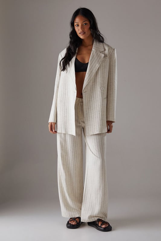 Boxy fit blazer with classic pinstripe pattern for a contemporary twist on tailoring
        Single button fastening creates a clean, streamlined silhouette
        Notched lapel collar adds traditional tailoring detail
        Long sleeves with structured shoulders for a confident, defined shape
        Linen-look fabric offers a textured finish with natural drape
    
    This Warehouse blazer redefines casual sophistication with its relaxed boxy silhouette and distinctive pinstripe pattern. The linen-look fabric creates a textured appearance whilst maintaining a fluid drape that moves beautifully with the body. Style as seen with the matching wide-leg trousers for a coordinated suit that conveys confidence without trying too hard. For daytime engagements, pair with a simple t-shirt and trainers for an effortlessly cool look. When evening calls, swap for a silk camisole and statement jewellery. This versatile piece transitions seamlessly from family gatherings to casual office environments, and even weekend brunches. The relaxed structure makes it ideal for layering over lightweight knits during transitional seasons, whilst the timeless pinstripe pattern ensures this blazer will remain a wardrobe staple for years to come.